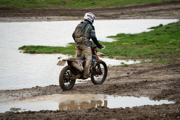Obraz premium motorcyclist taking their off-road bike through muddy and very wet terrain, Wiltshire UK