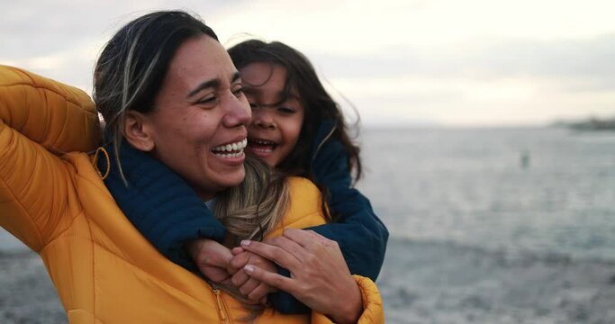 Latin girl hugging her mother on the beach at sunset during winter time - Mother day concept