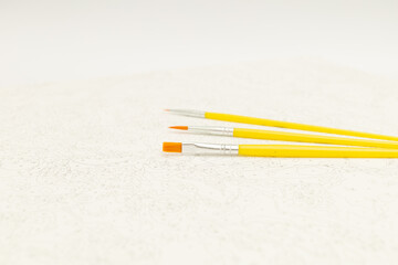 Brushes for painting yellow on white canvas