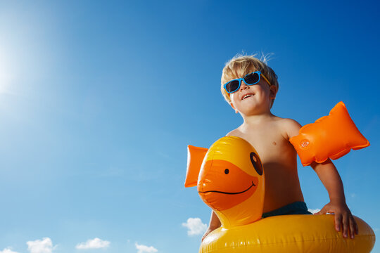 Low clos-up portrait of boy with inflatable yellow duck buoy