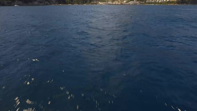 Establishing shot of Capri island and town over deep blue ocean, fast moving forward