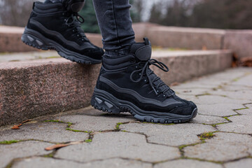 Black sneakers on the legs in black jeans at the girl on the street