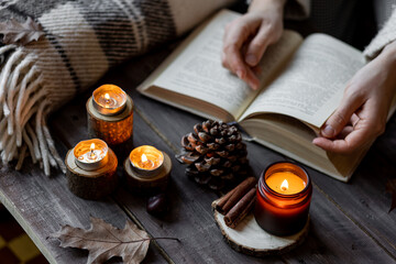 Cozy autumn or winter composition with aromatic candle, wool sweater. Aromatherapy, home atmosphere...