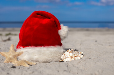 Santa Claus hat and starfish on the sandy beach