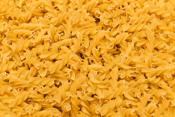 Uncooed Fusilli Pasta - Background. Texture of Bright Golden Dry Macaroni
