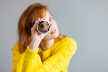 Young woman playing I spy with the camera looking through a rolled cylinder of paper with one eye...