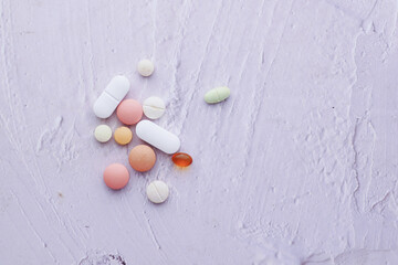 top view of many colorful pills and capsules spilling on white 