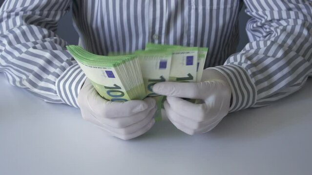 A man wearing medical protective gloves counts euro money during the coronavirus pandemic covid - 19