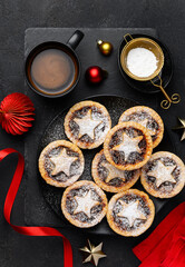 Traditional Christmas mince  pies with dried fruits on a black plate with a cup of coffee. English festive dessert. Top view © Olga Romankova