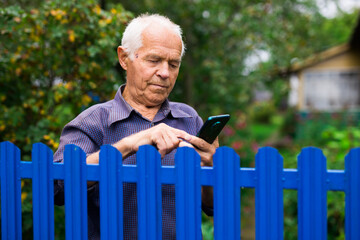 Elderly man writes message on smartphone. Concept of using digital gadgets by elderly