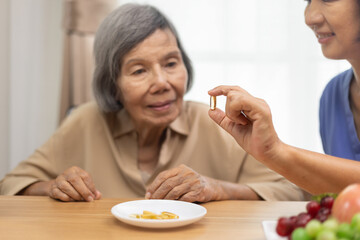 Caregiver entering fish oil to elderly woman at retirement house.