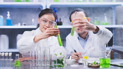 Two scientists's hand is holding and compare test tube with green substance. Concept of...