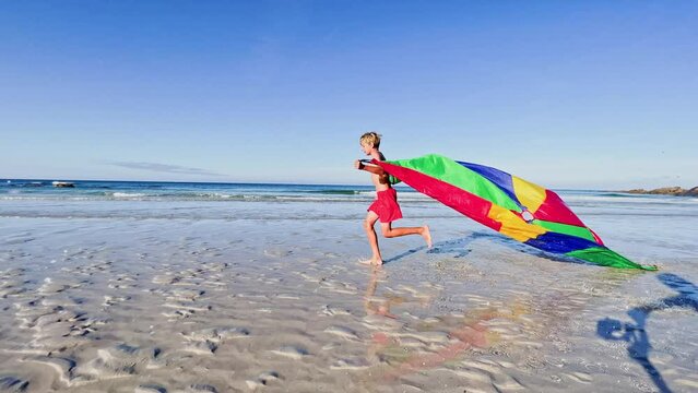 Boy with parachute fly on wind run at ocean beach profile image