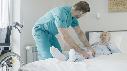 Male therapist helping injured patient, doing rehabilitation exercise, muscle recovery