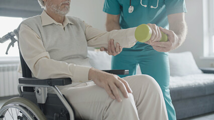 Man with disability doing exercise with assistance of physical therapist, mobility impairment