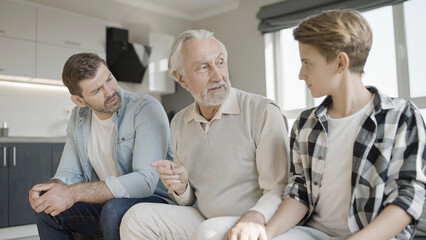 Young man and son trying to cheer up upset grandfather, family support