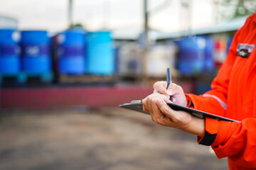 A safety office is writing on paper clipboard during perform safety audit with chemical storage in...