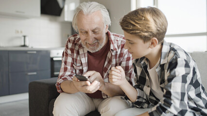Child explaining senior grandparent how to use social network app on smartphone