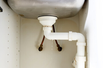 Kitchen sink plumber damage, water dripping from the pipe under the kitchen sink. 