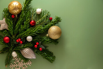 Christmas background with fir branches, decorations, golden baubles on green background. Flat lay, top view, Copy space.