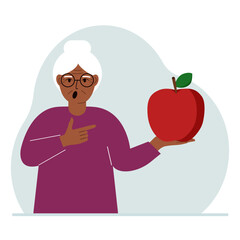 A old woman holds a fresh and red apple in his hand. Woman eats an apple. Healthy food concept.