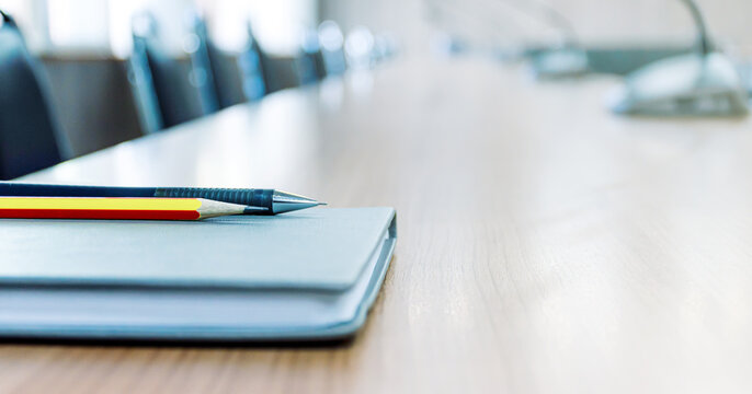 Pencil and notebook on table in meeting room with copy space