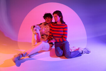 Stylish couple sitting in neon light