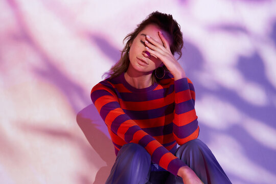 Woman in colorful clothes sitting in projector light