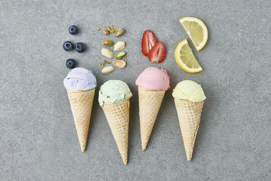 Row of waffle cones with assorted gelato arranged on gray table
