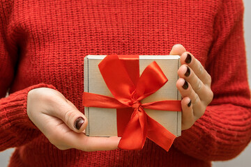 Woman's hands holding craft paper gift present box with.female winter manicure.Christmas New Year