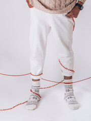 stylish man in white trousers and socks. Men socks on his feetwith red beads. Socks with ornament.