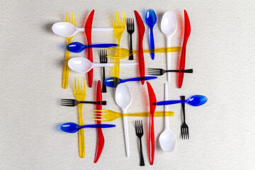 Top view colorful plastic utensils on white background. Forks with spoons and knives.