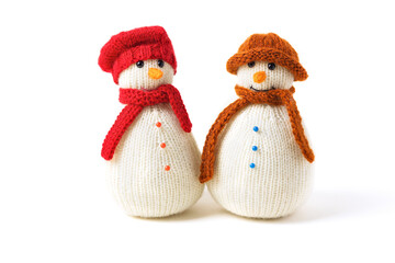 Two knitted snowmen on a white background in red and brown hats. Merry Christmas and New Year 2023 greeting card