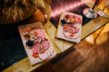 Snacks on plates in a restaurant. Decorations on the table. Sausage, olives, cherry tomatoes, salmon.