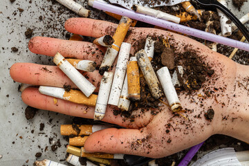 Close up hand holding pile of cigarettes with dirt. Concept of enviroment pollution.