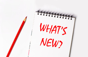 Red pencil and white notepad with the text WHAT'S NEW