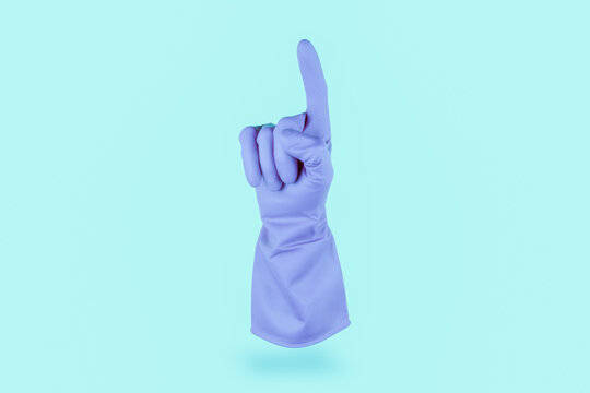 Light blue cleaning glove floating in the air counting 1 oor pointing up on cian background