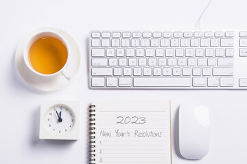 Conceptual,mouse and keyboard with clock and tea on white blackground work space.open diary with new year's resolutions 2023