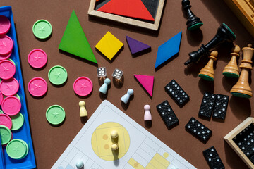 Different desktop games, figures, dices, parts on the brown table. Home entertaiment, indoor games	