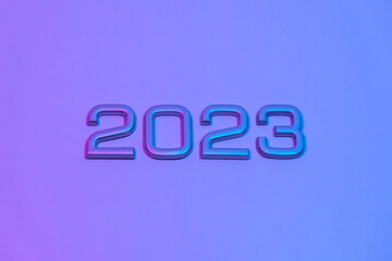 The numbers 2023 in neon light. New Year 2023 on a blue pink background. The postcard is in purple. Merry Christmas.