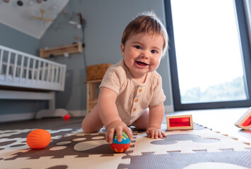 Cute happy baby boy playing toys in his child room