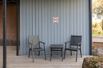 No Smoking area at wooden terrace of a Scandinavian-style country house with furniture - chairs and a table