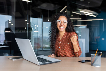 Portrait successful Hispanic business woman office worker with curly hair smiling and looking at...