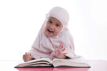 Asian Malaysian Muslim kid is reading the Quran. The Quran is indicated as the guided book for all Muslim and it is direction to be on the heaven of God.Mosque,Islam,religion and knowledge concept.