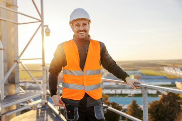 Portrait of an heavy industry worker standing on the height and smiling at the camera.