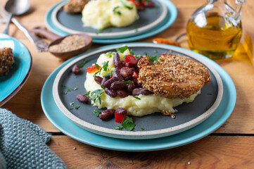 Baked chicken with sesame seeds, mashed potatoes and kidney bean, pepper vegetable on a plates