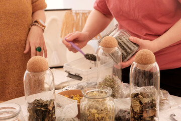 Herbal tea collection. Glass jars with lids. Master class on cooking, training. The hands of the participants are large against the background of jars and bowls with herbs. Ecological, clean.