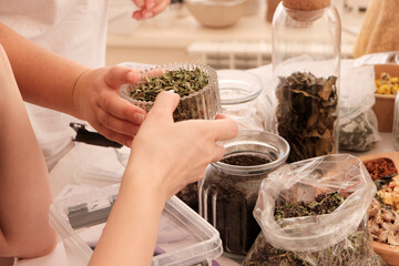 Herbal tea collection. Glass jars with lids. Master class on cooking, training. The hands of the participants are large against the background of jars and bowls with herbs. Ecological, clean.