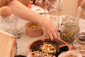 Herbal tea collection. Glass jars with lids. Master class on cooking, training. The hands of the participants are large against the background of jars and bowls with herbs. Ecological, clean.