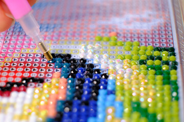 Diamond painting with pen closeup. art therapy concept. Laying out a diamond mosaic improves a...